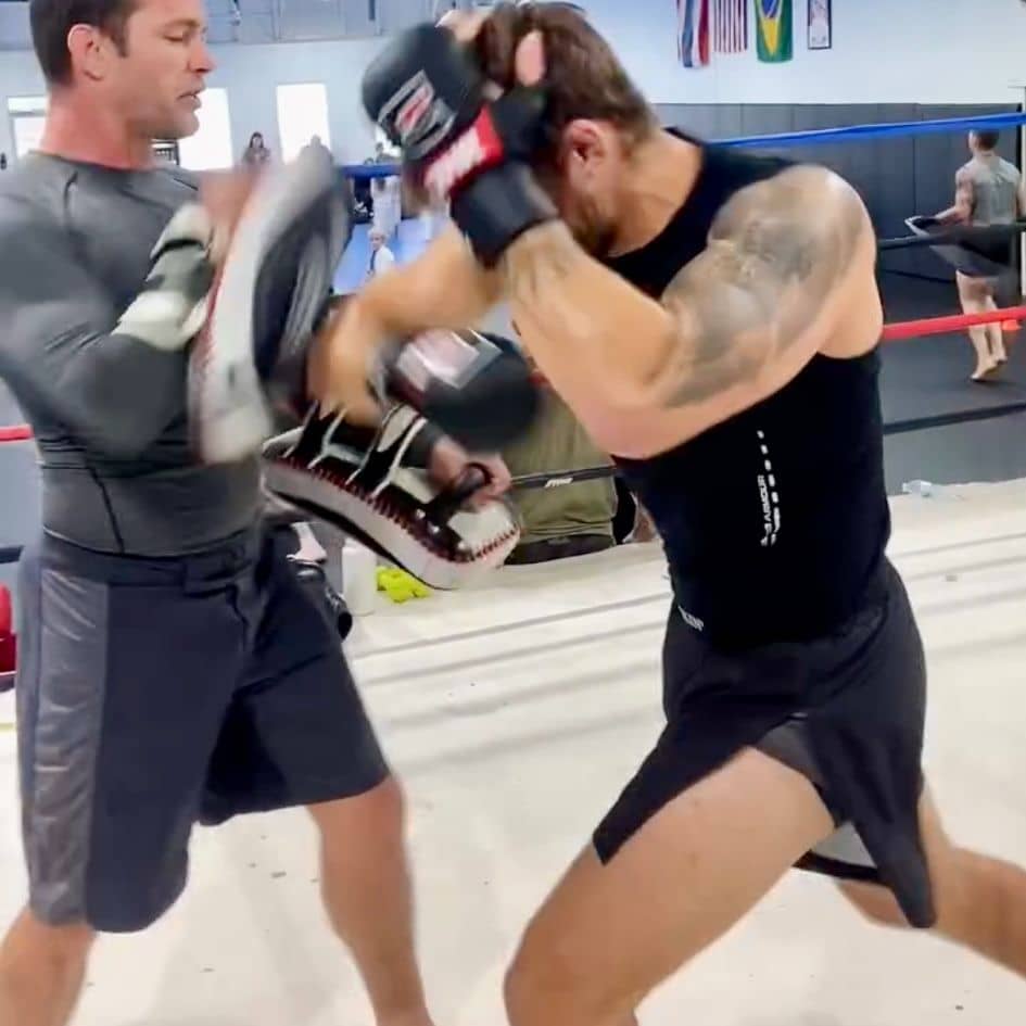 Fighter hitting pads with elbow while wearing Kickin' Combat "Origins" high cut gladiator MMA shorts