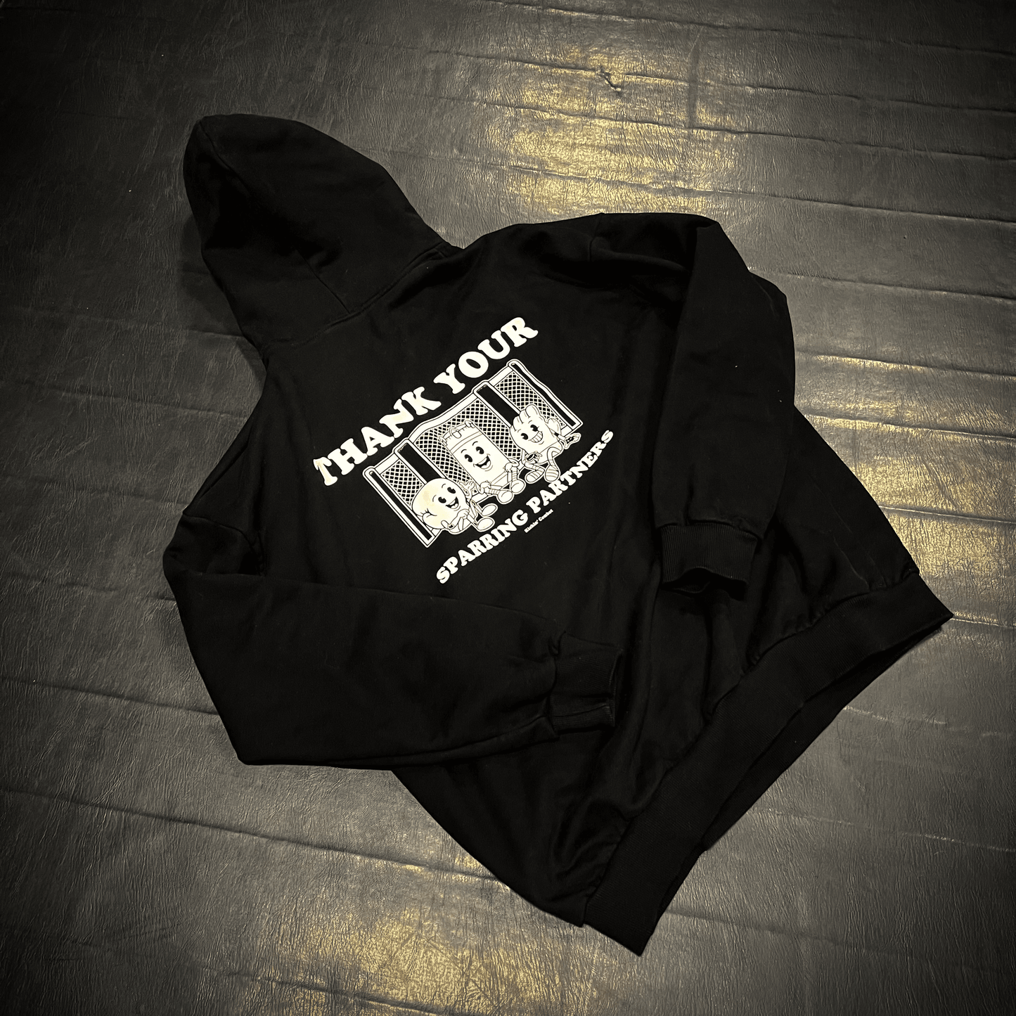 "Thank Your Sparring Partners" black hoodie back on fight gym mat